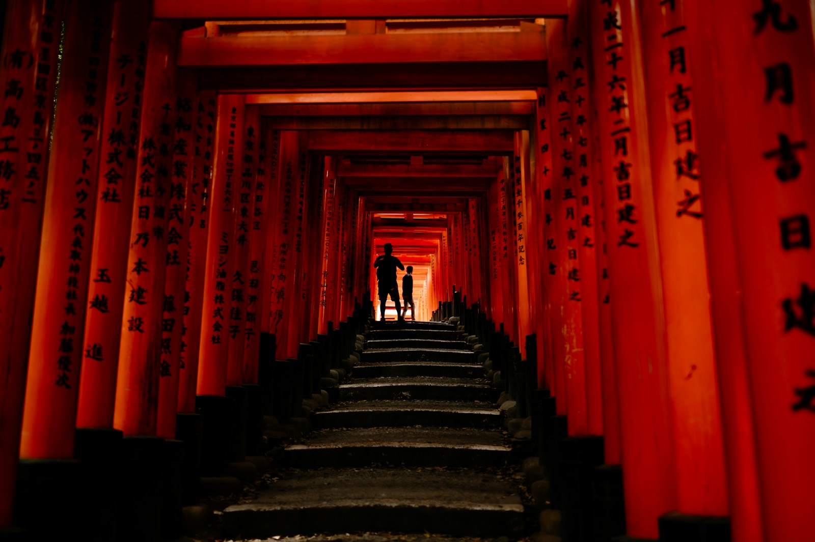 two people standing in a tunnel of red tori tori tori tori tori tori tori tori